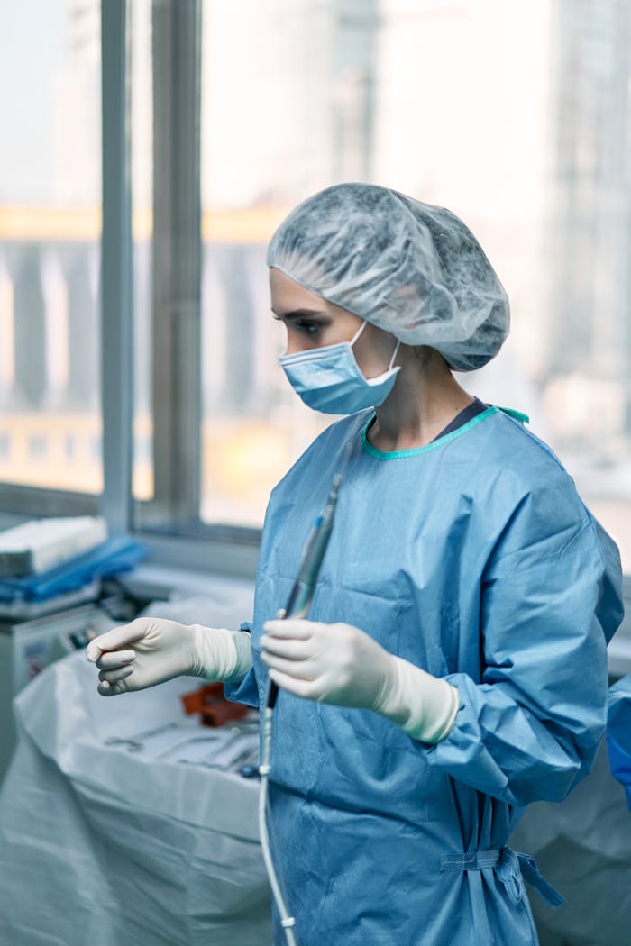 A female surgeon in a surgical gown and mask preparing for an operation in a hospital operating room.